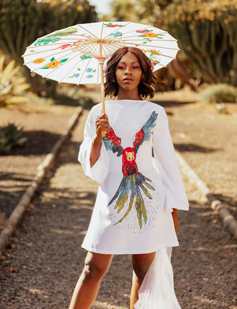 Mujer con vestido blanco y estampado de loro, sombrero de sol. - Gianluca Urraso